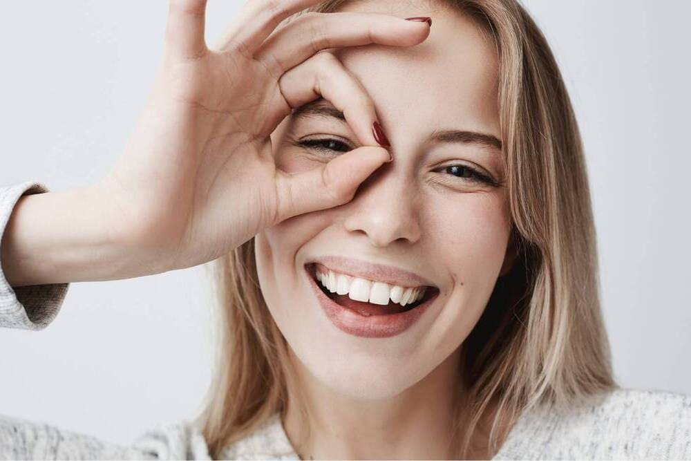 chica sonriente haciendo gesto cara mano